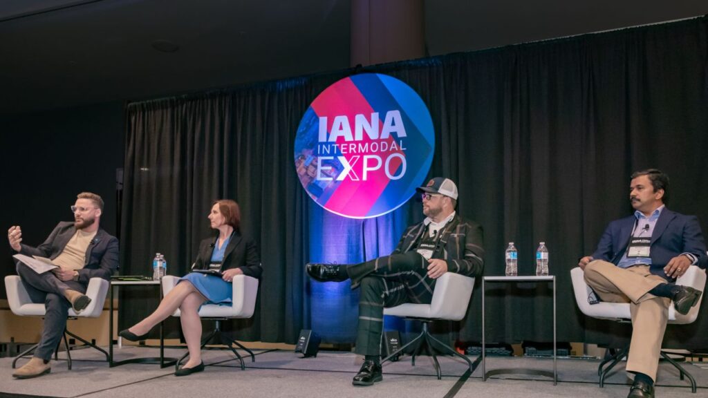 four people, including Maneet, sitting on a stand in chairs participating in an Intermodal panel at IANA Expo