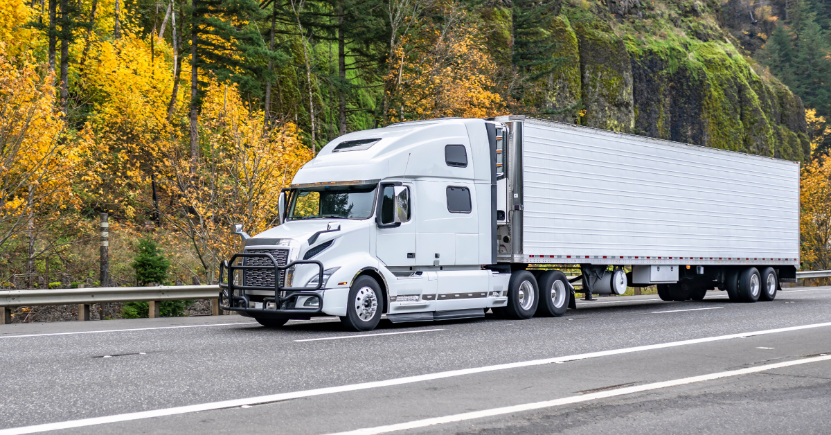 a semi-truck pulling a refrigerated trailer down the road
